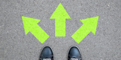 2 a pair of shoes standing before three arrows on the pavement, one pointing left, one pointing center, and one pointing right